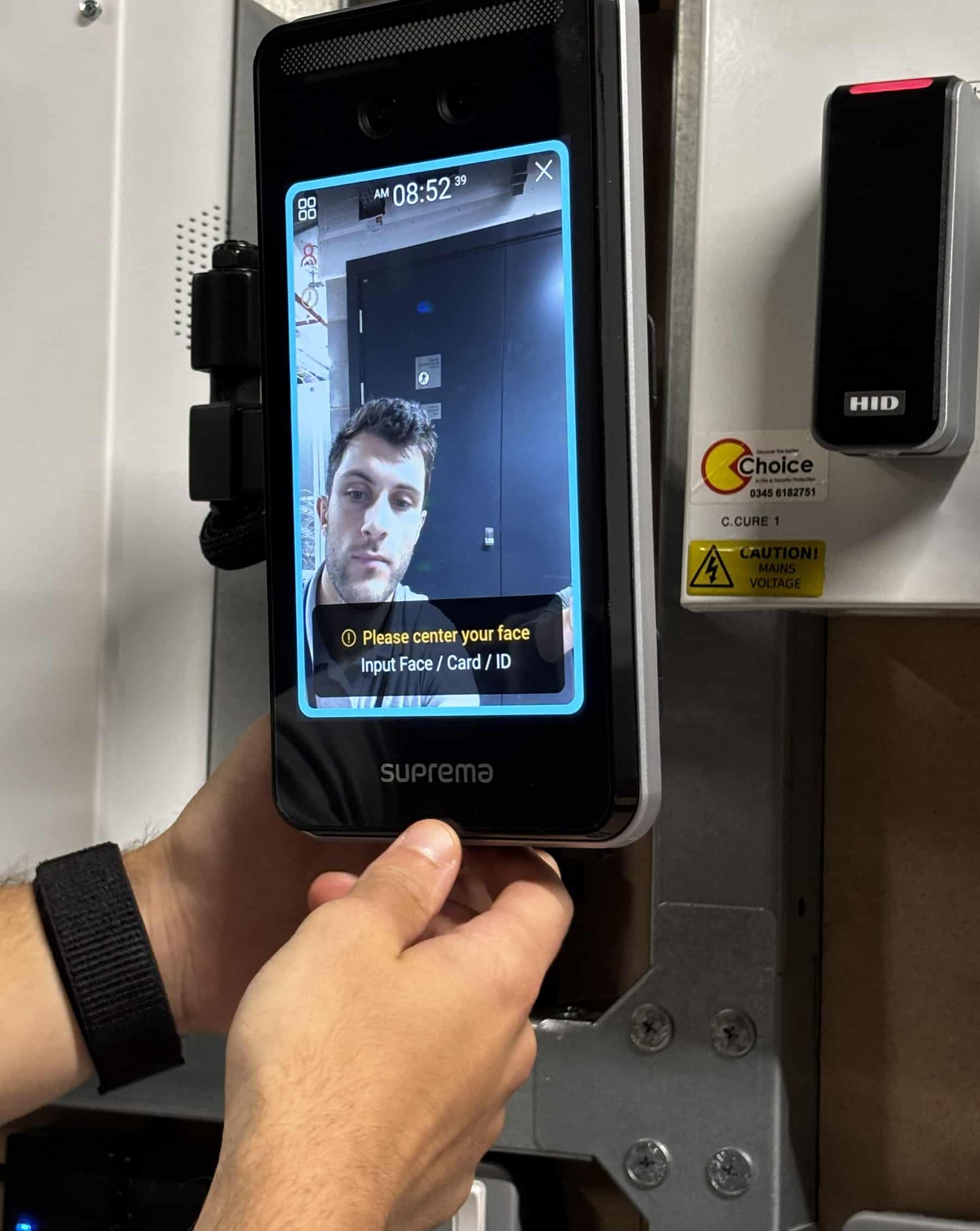 Person using a facial recognition device for access control.
