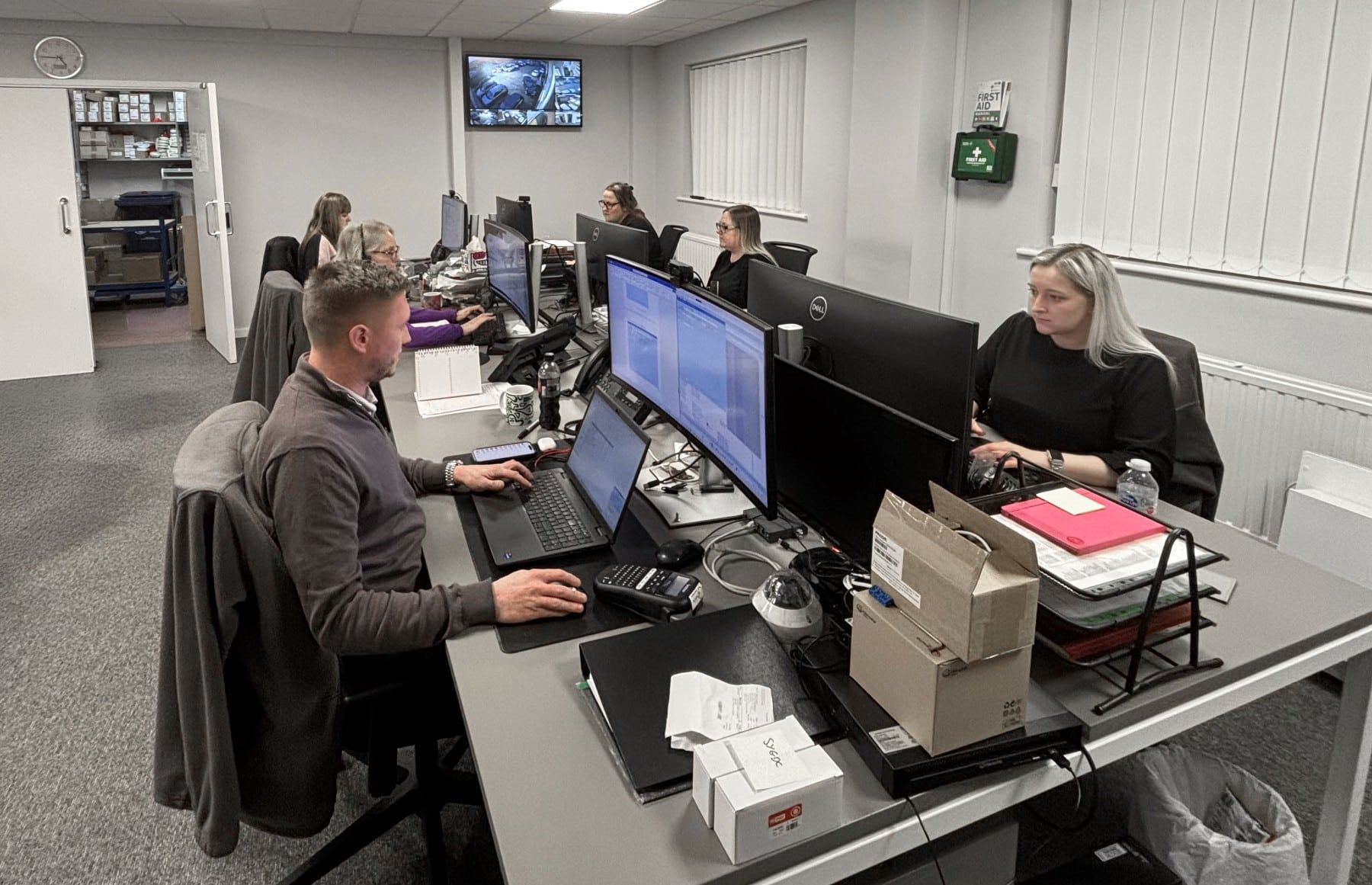 People working at desks with computers in an office setting.