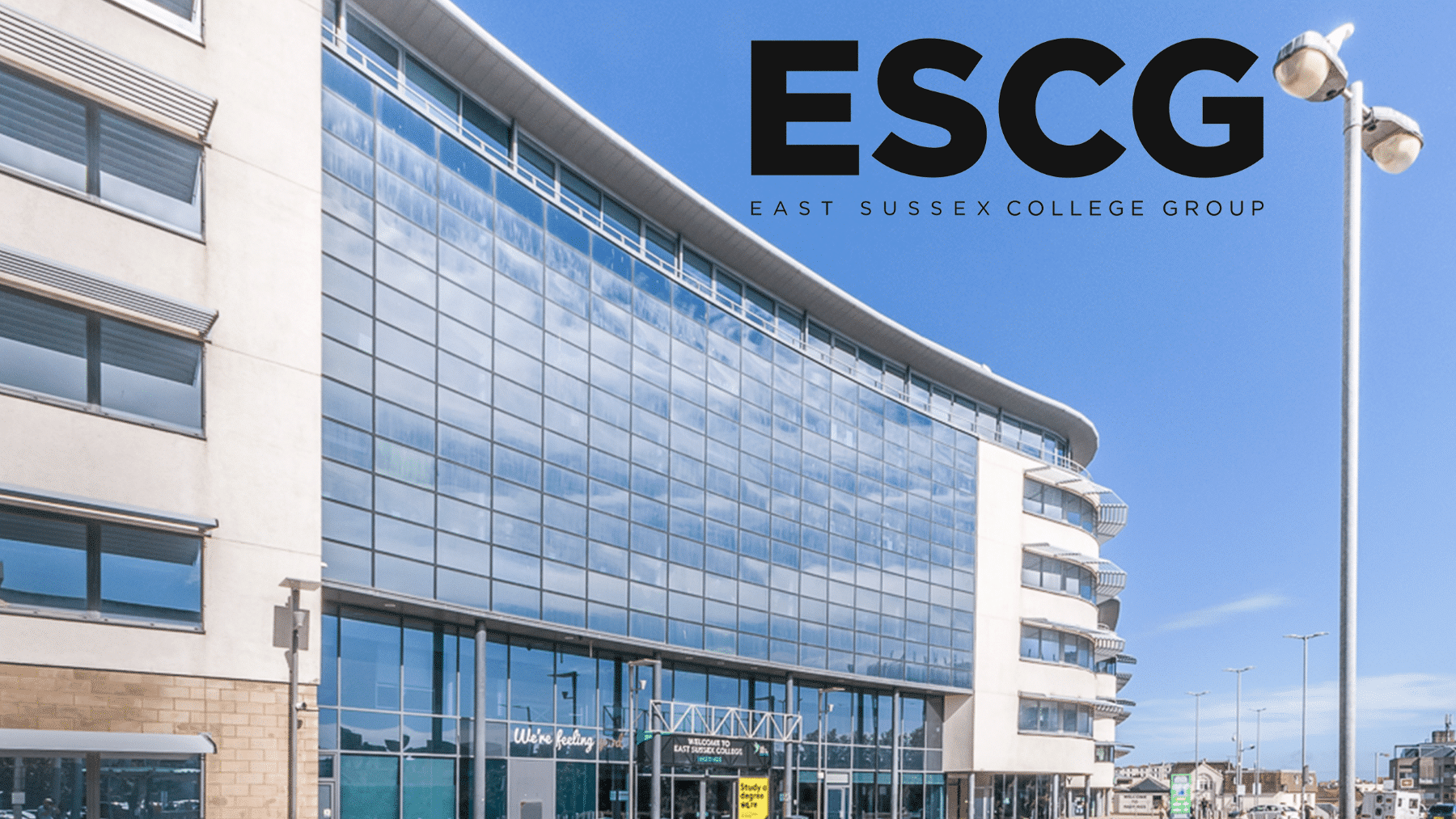 Modern glass-fronted college building with "ESCG East Sussex College Group" logo in the sky.