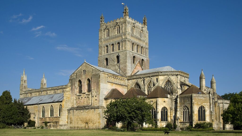 Tewkesbury Abbey Large stone abbey with a tall central tower under a clear blue sky.